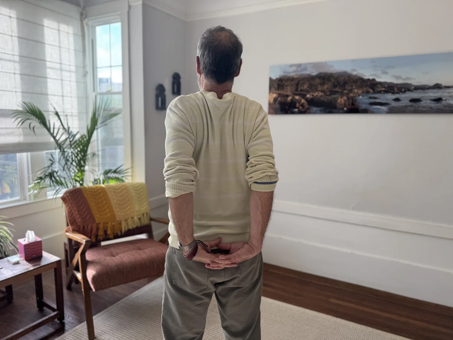 Garrett in a yellow sweater with hands clasped behind his back
